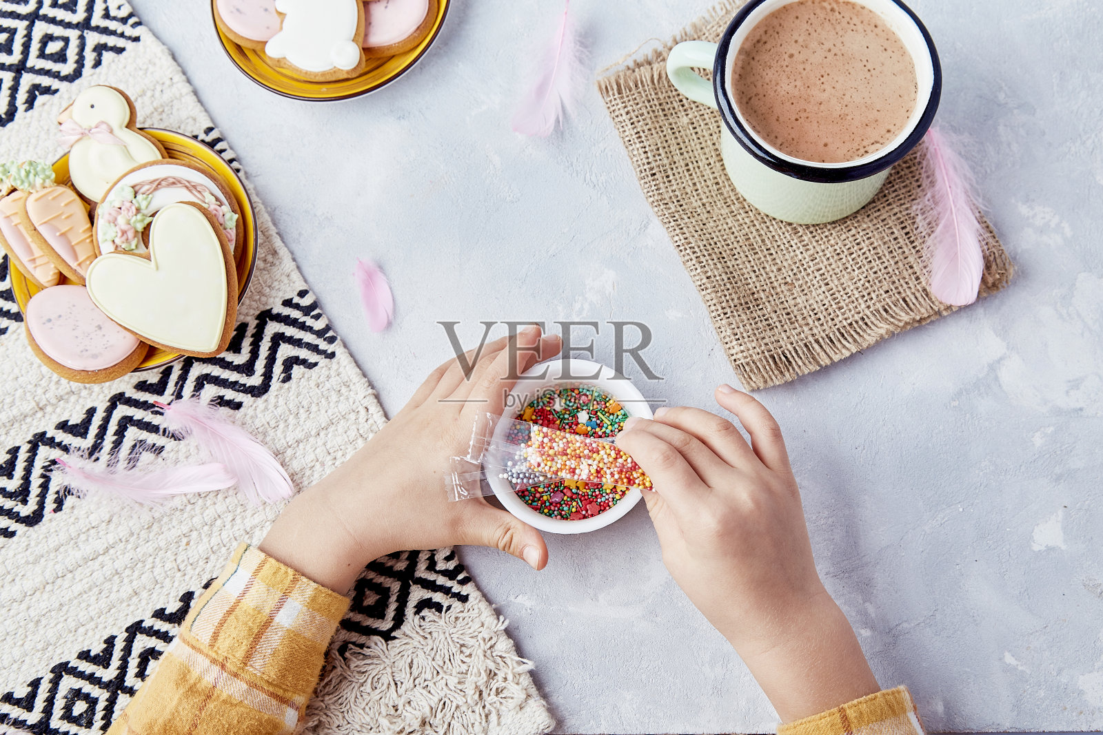 复活节的气氛充满了节日的味道,孩子们在饼干上撒上糖屑装饰照片摄影图片