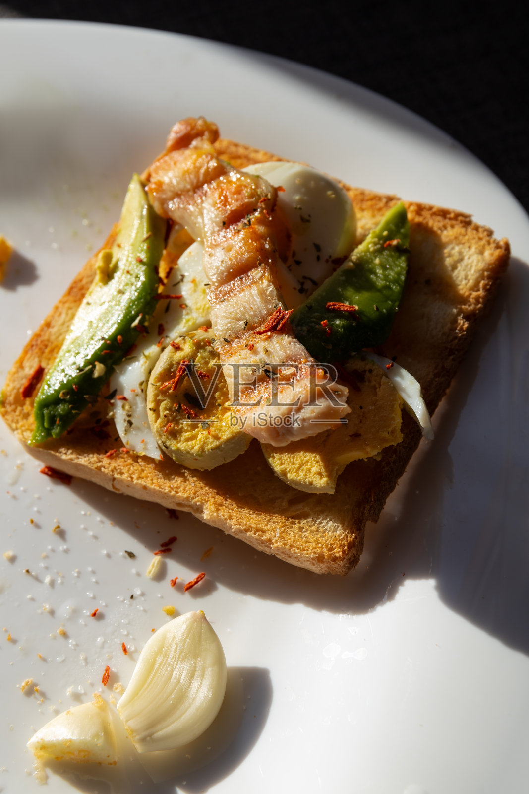 一份健康的早餐,上面有烤面包、煮鸡蛋、牛油果和烤鸡胸肉,放在白色的盘子里,沐浴在窗外的阳光下照片摄影图片