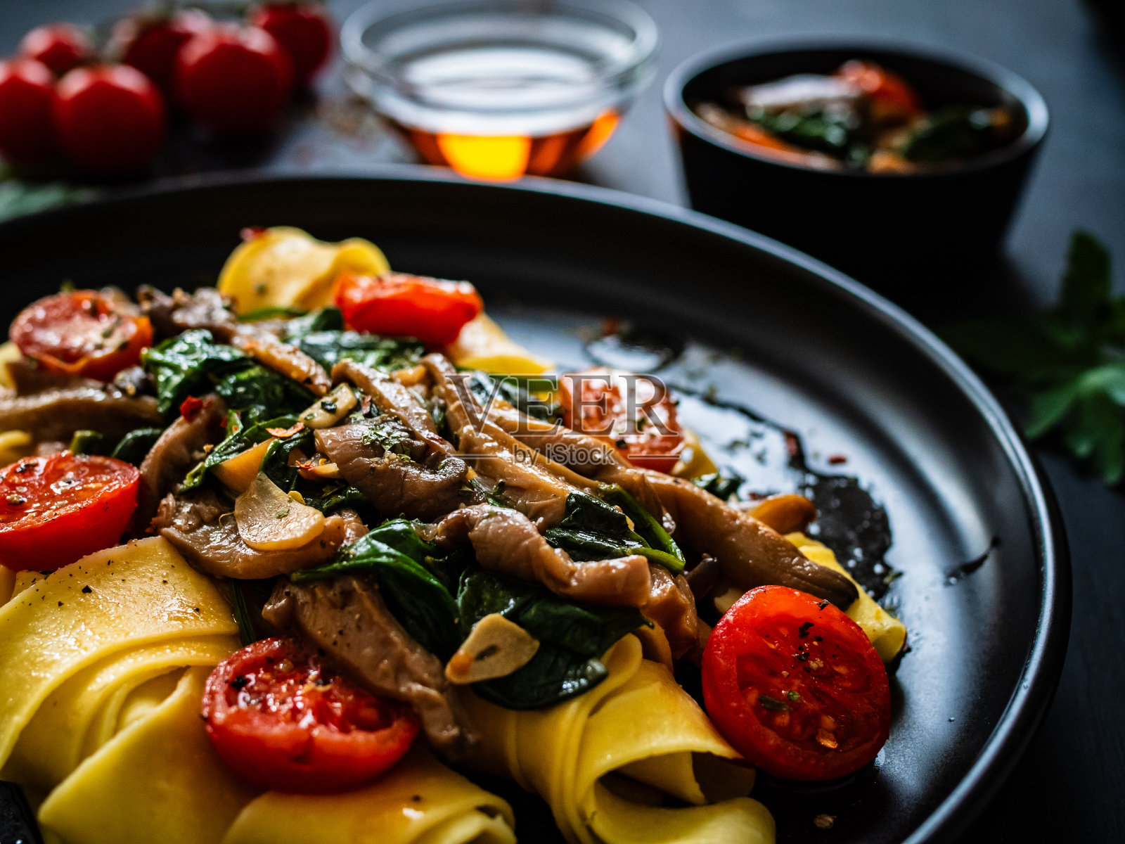 黑桌上的蘑菇菠菜西红柿面条照片摄影图片
