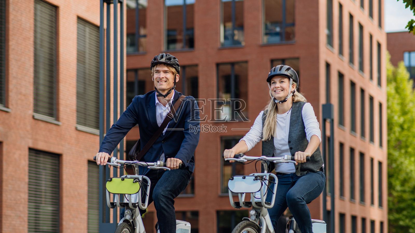 夫妻在城市中穿梭,在街上骑着自行车聊天和散步。在漫长的工作日后骑自行车下班的中年城市上班族。照片摄影图片