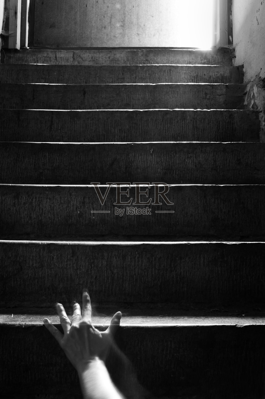 一只手爬上楼梯的黑暗影像。照片摄影图片