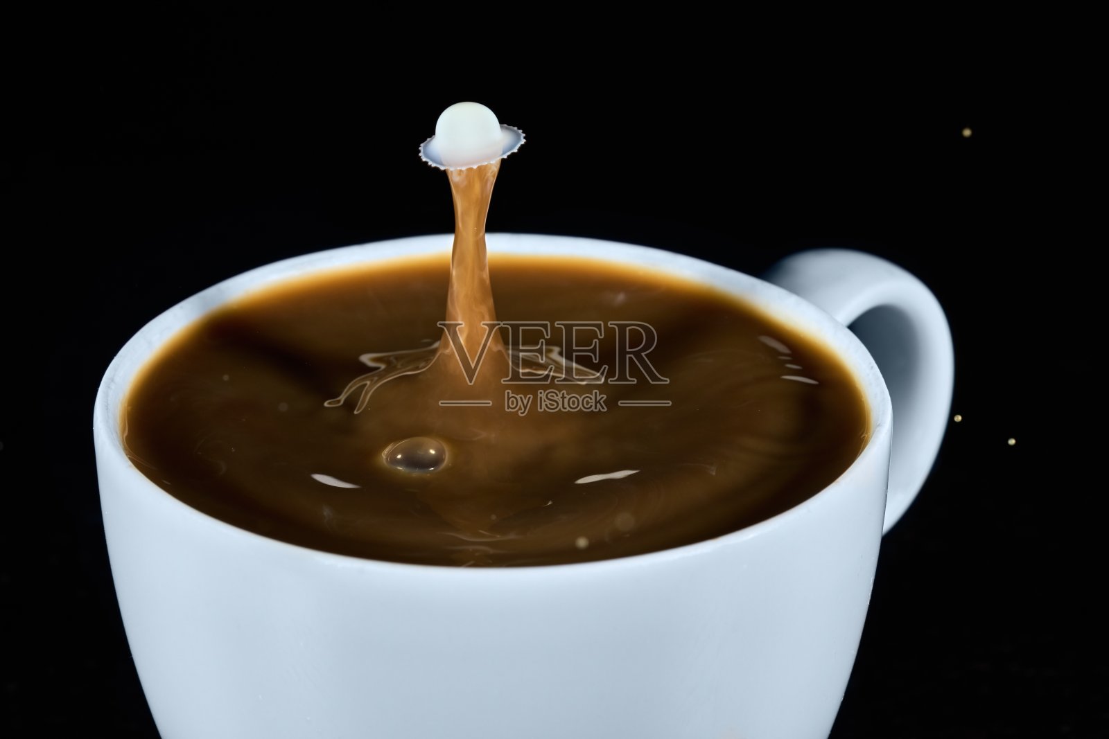 一杯咖啡里两滴碰撞的牛奶照片摄影图片