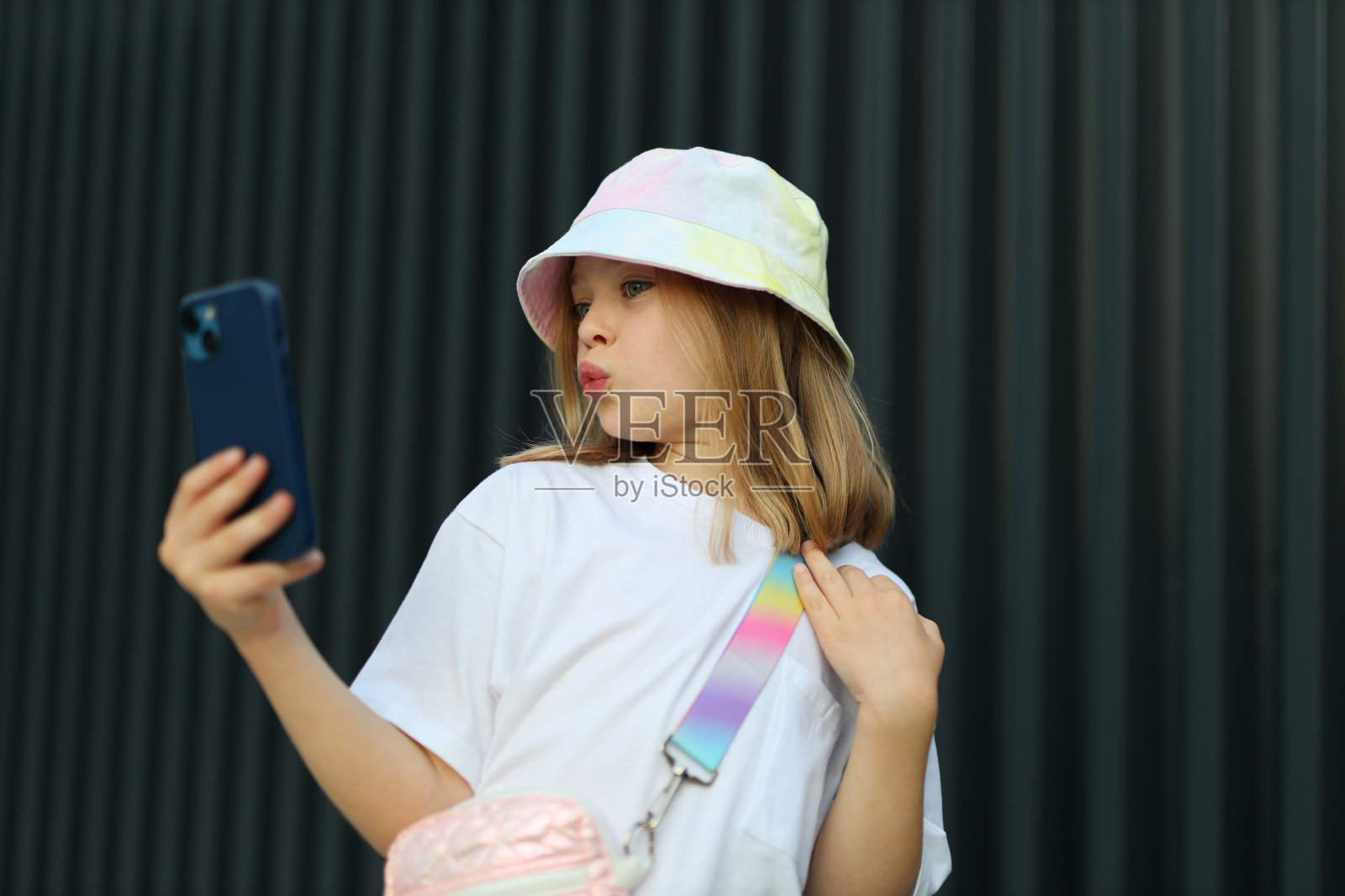 一个时尚的小女孩在城市里享受夏天,在户外用智能手机自拍。照片摄影图片