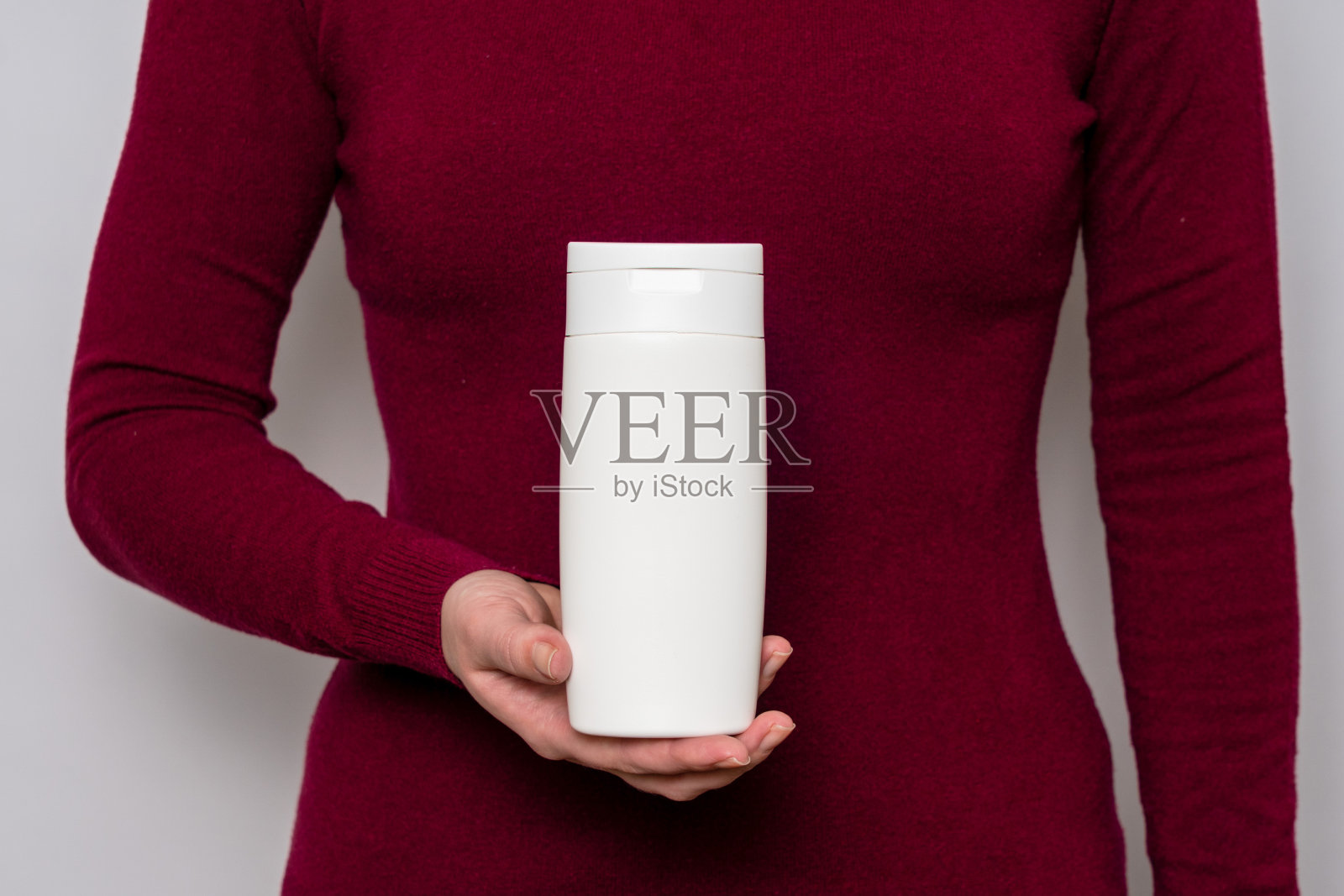 洗发水或护发素的包装,在女士手中的位置。瓶装化妆品照片摄影图片