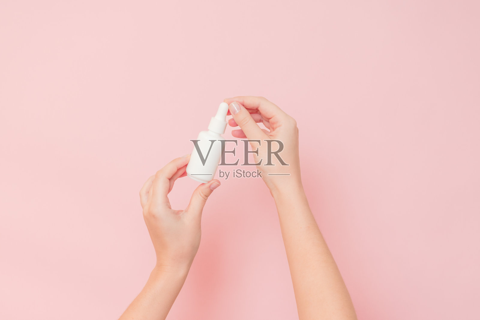 白色的瓶子里装着精华液或精油(透明质酸和胶原蛋白),底色为粉红色。护肤化妆品概念,美容传单照片摄影图片