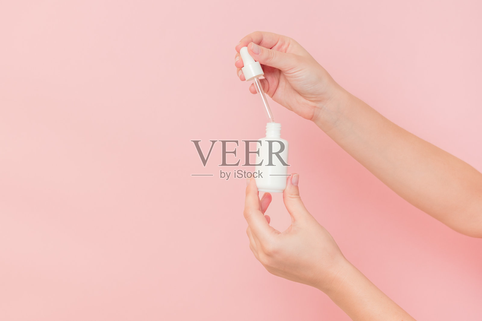 手持玻璃化妆品瓶血清(透明质酸和胶原蛋白)在粉红色的背景。美丽的概念照片摄影图片