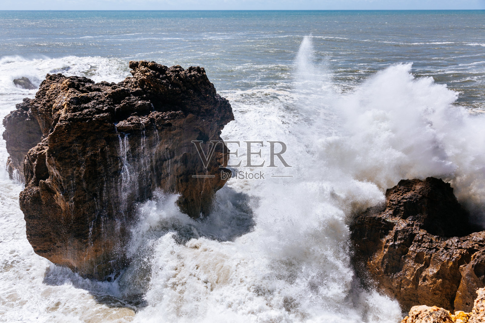 强大的海浪冲击着葡萄牙纳扎雷的岩石海岸线。照片摄影图片