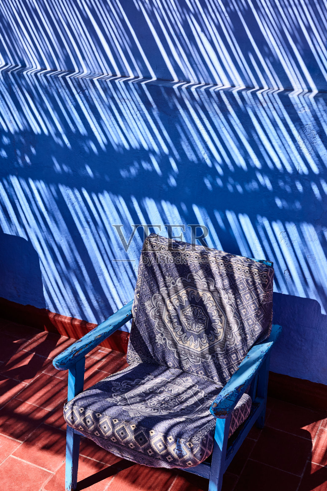 椅子与蓝色墙壁与阴影图案在舍夫沙万,摩洛哥照片摄影图片