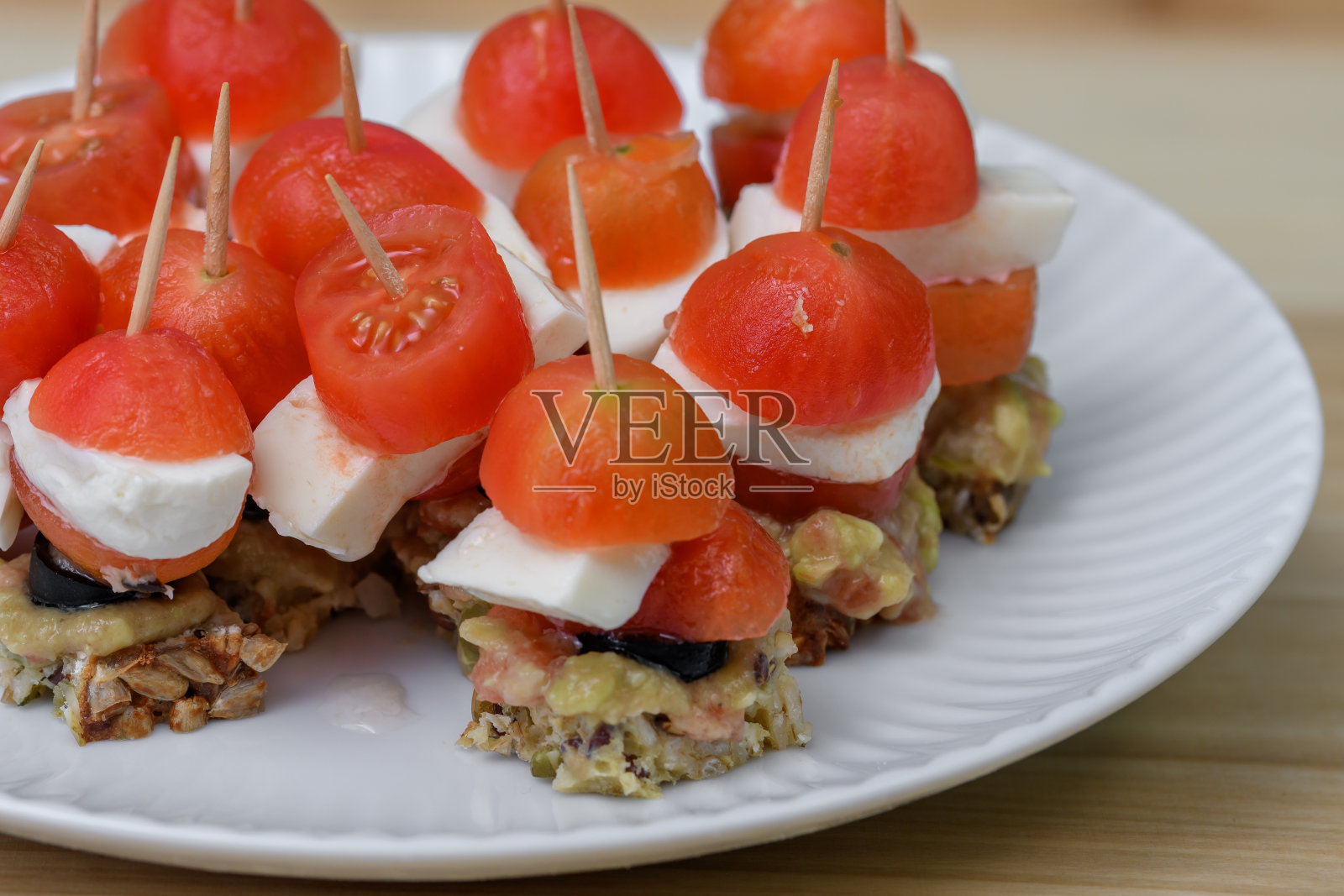 盘子里放着泡菜,牙签上放着圣女果、鳄梨、面包和马苏里拉奶酪照片摄影图片