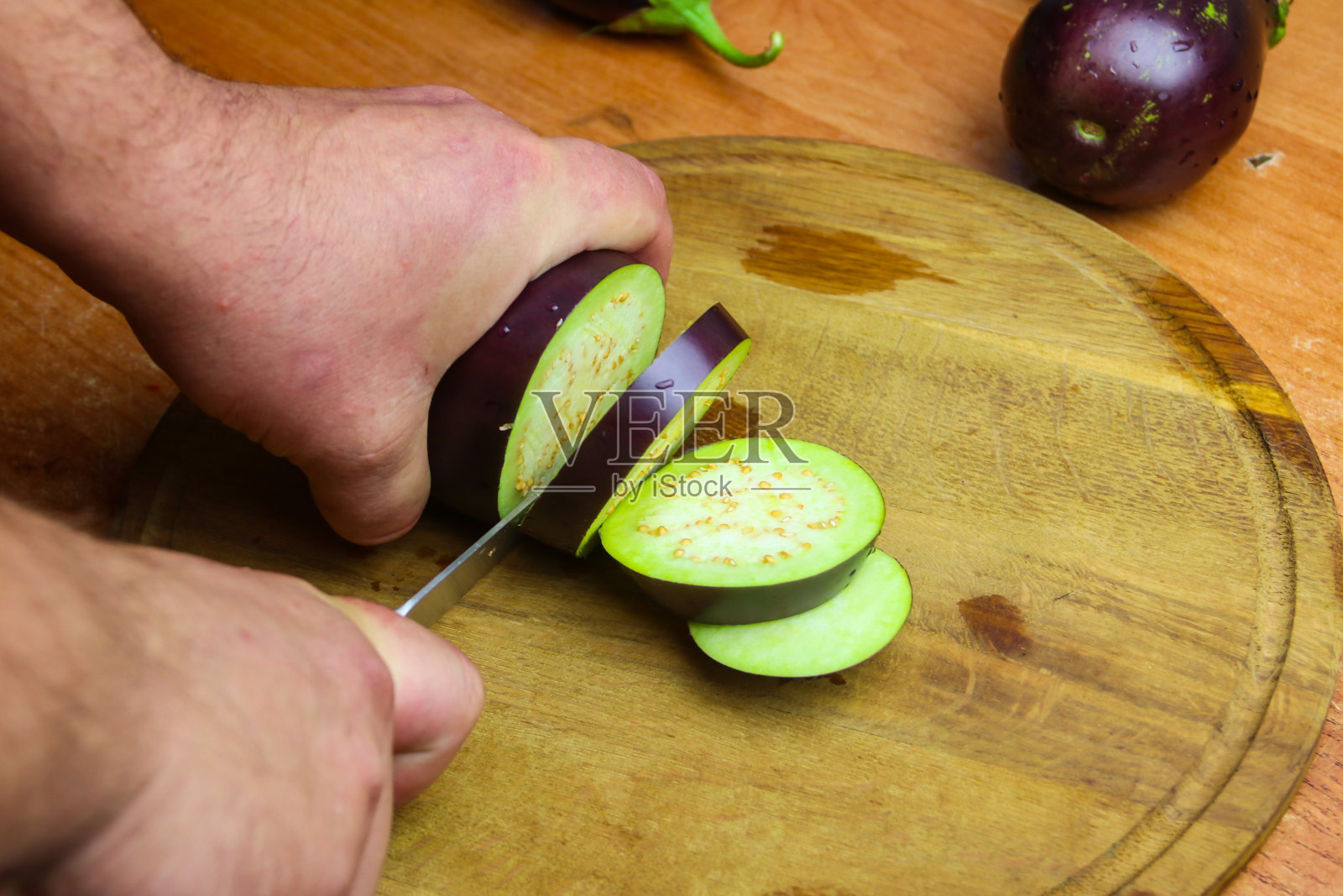 厨房切菜板上男性手切茄子的特写镜头照片摄影图片