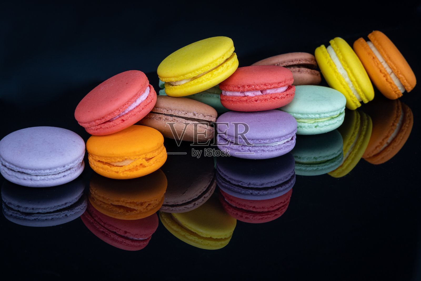 大量的彩色马卡龙在黑色的背景与反射。传统法式甜点照片摄影图片
