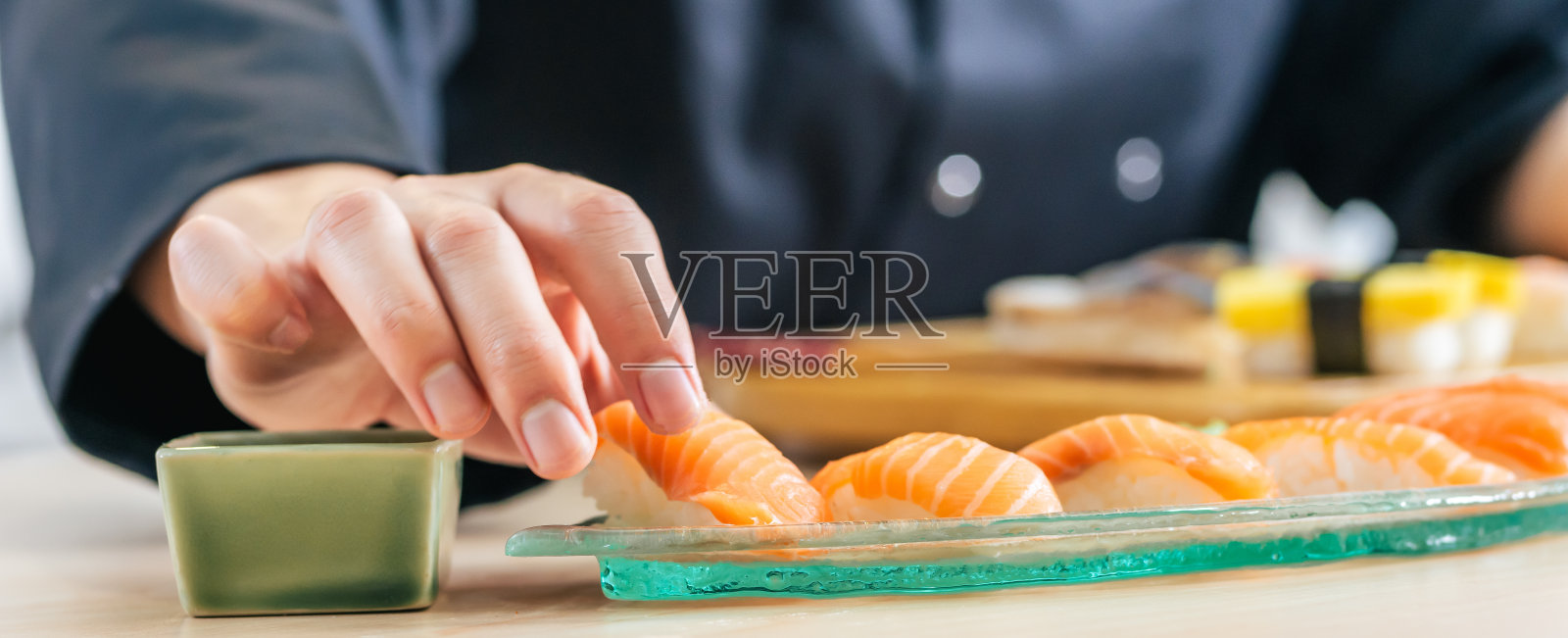 近距离和选择性聚焦厨师手把鱼放在饭团,烹饪和制作寿司,日本传统街头食品。餐厅,酒店概念。照片摄影图片