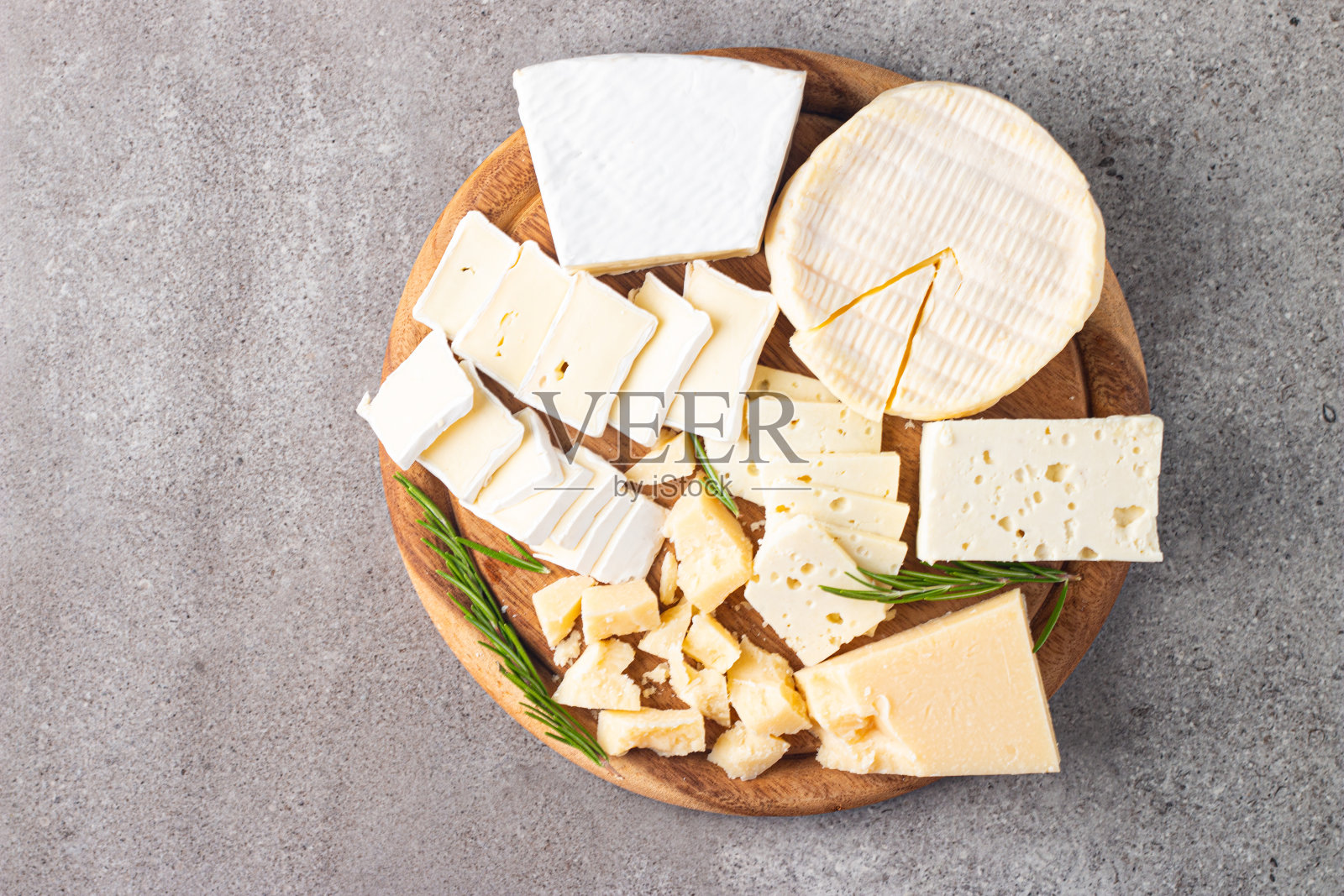 木板上有各种奶酪和橄榄。布里干酪。乳酪。帕尔马干酪,菲达干酪,蓝纹奶酪。意大利奶酪,法国奶酪。照片摄影图片