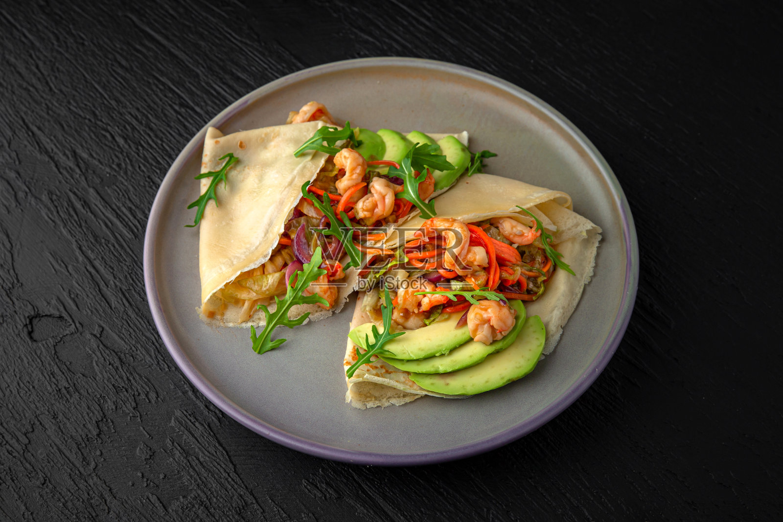烤饼配虾、牛油果和蔬菜放在陶瓷盘子里,背景是深色纹理。餐厅的菜单照片摄影图片