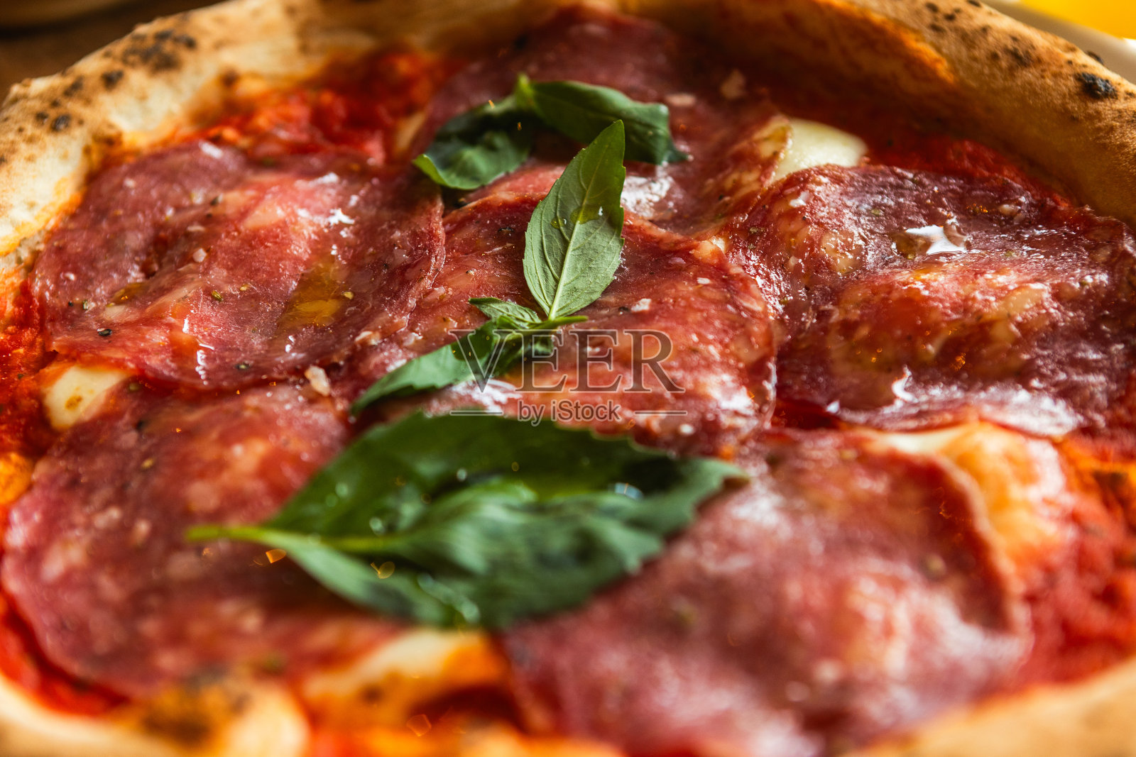 在餐厅里,用罗勒叶装饰的意大利腊肠披萨配上橘子鸡尾酒照片摄影图片