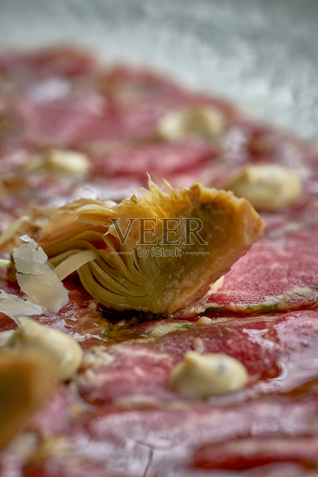 意大利牛肉片配洋蓟,盘里有芝麻菜。美味的小吃照片摄影图片
