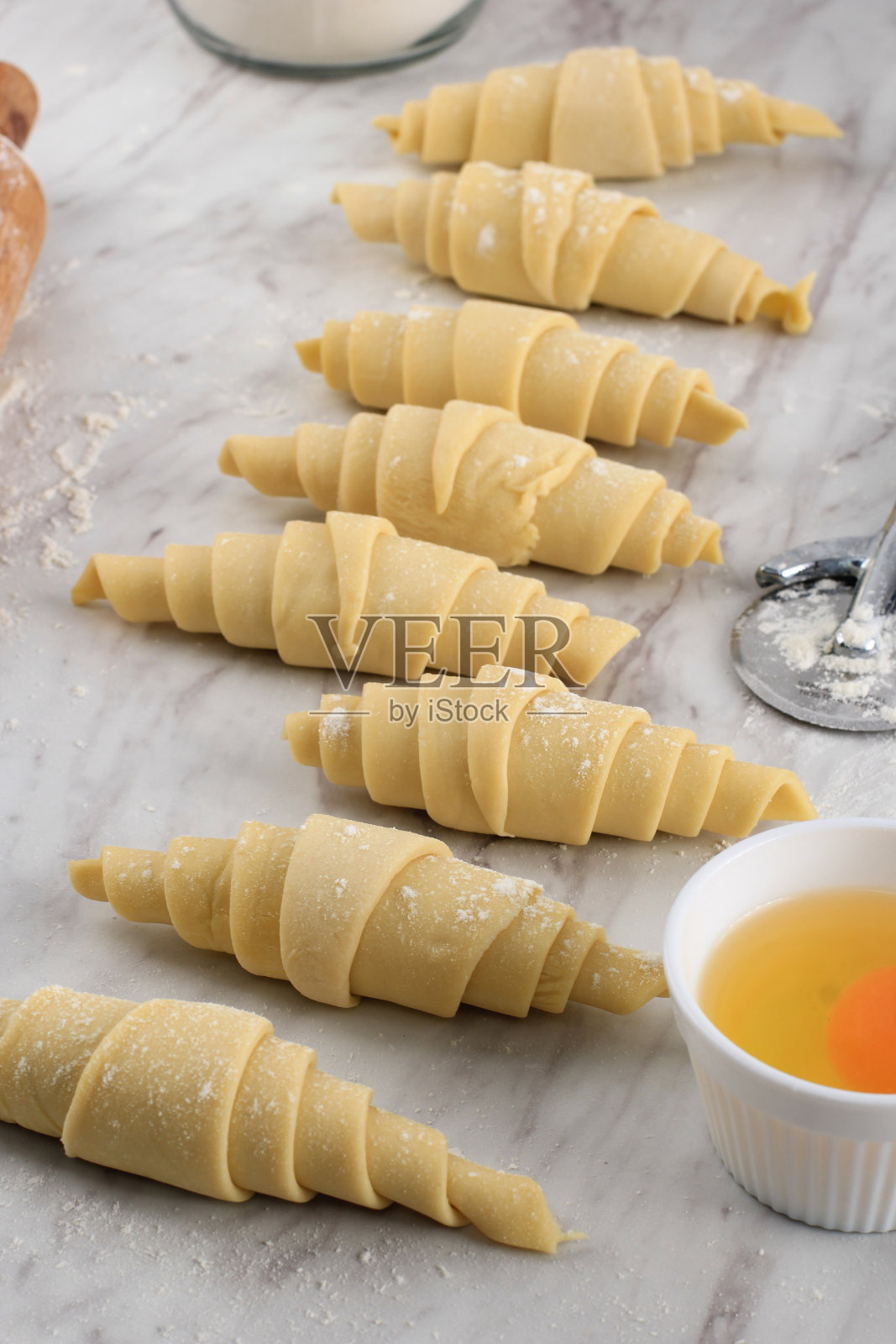 制作牛角包,白色大理石桌上的牛角包。厨房烘焙准备过程照片摄影图片