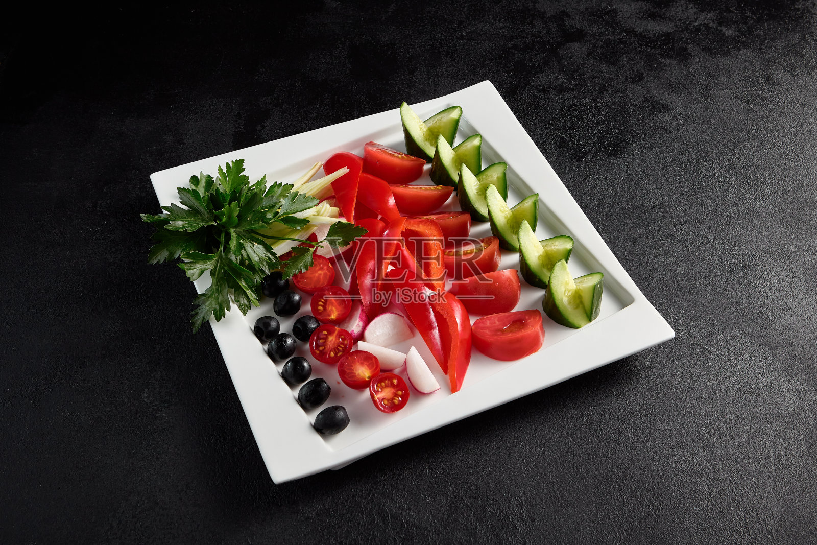白色方形盘子里有橄榄、西红柿、甜椒和黄瓜照片摄影图片