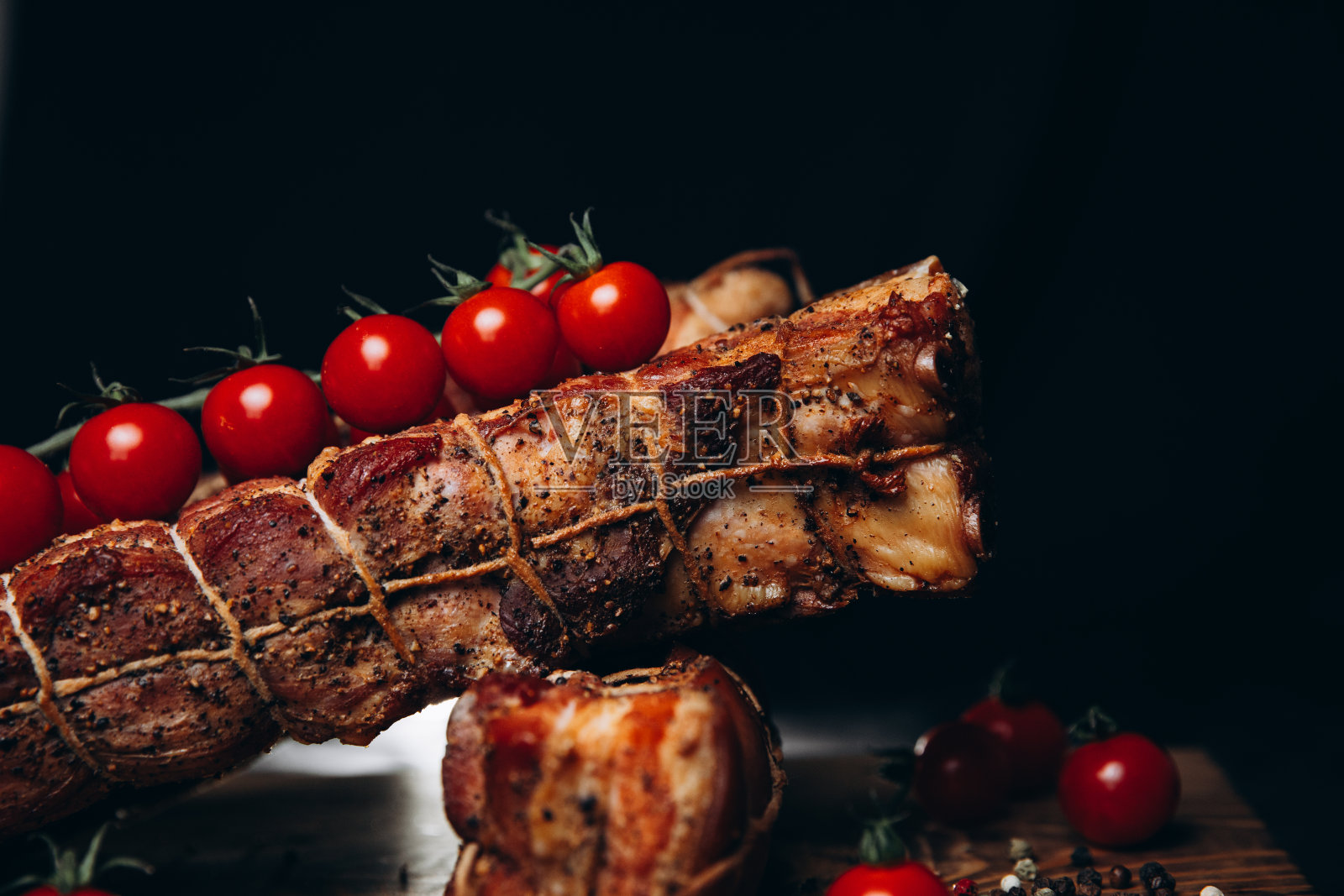 木托盘上的熏猪肉,还有胡椒和圣女果照片摄影图片