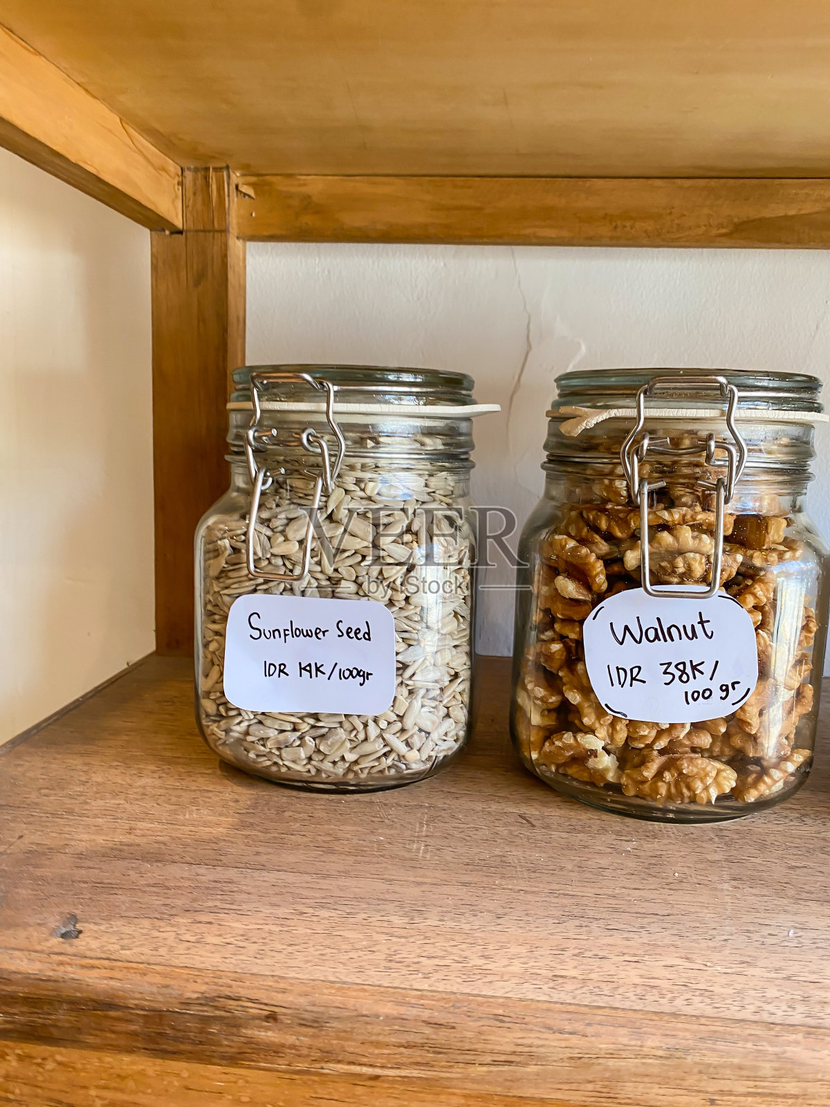 去皮的葵花籽和核桃装在透明的玻璃罐中出售。一家出售各种调味品、配料、调味料、干香草和香料的日用品商店。照片摄影图片