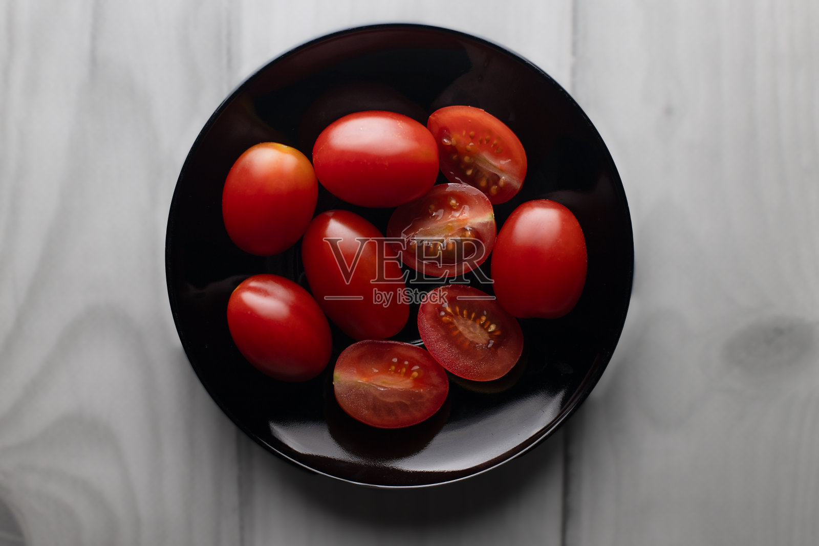 黑色圆盘子里的圣女果。照片摄影图片