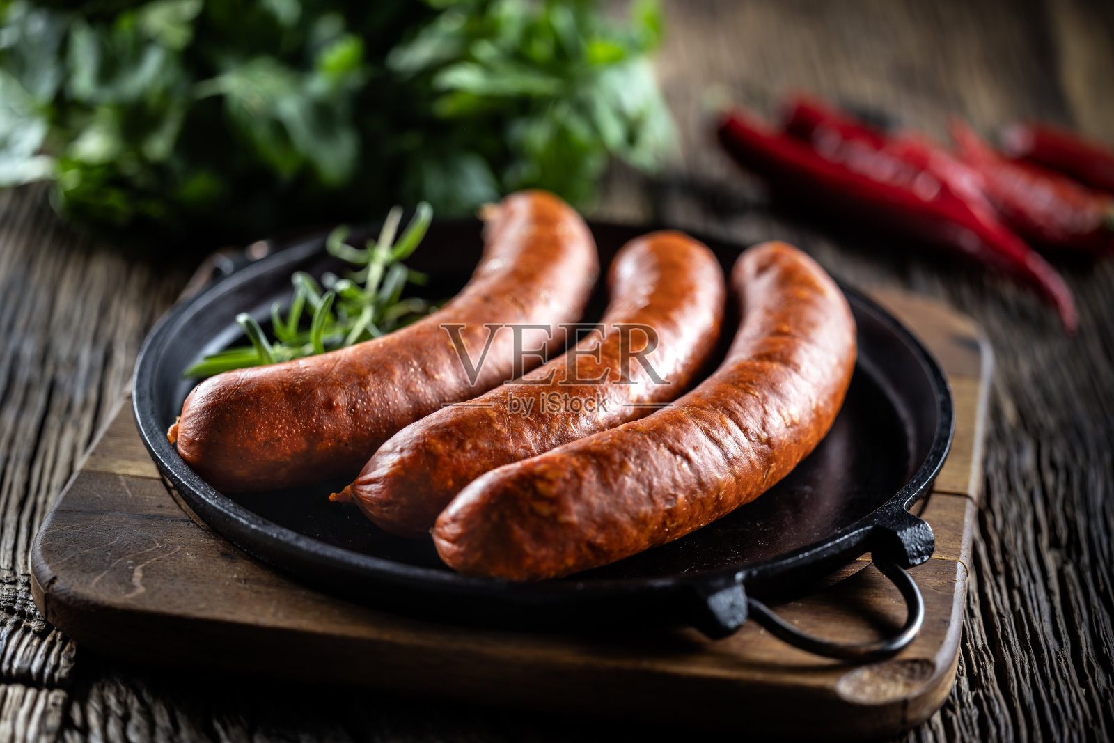 铁锅中加入迷迭香胡椒猪肉熏肠。照片摄影图片