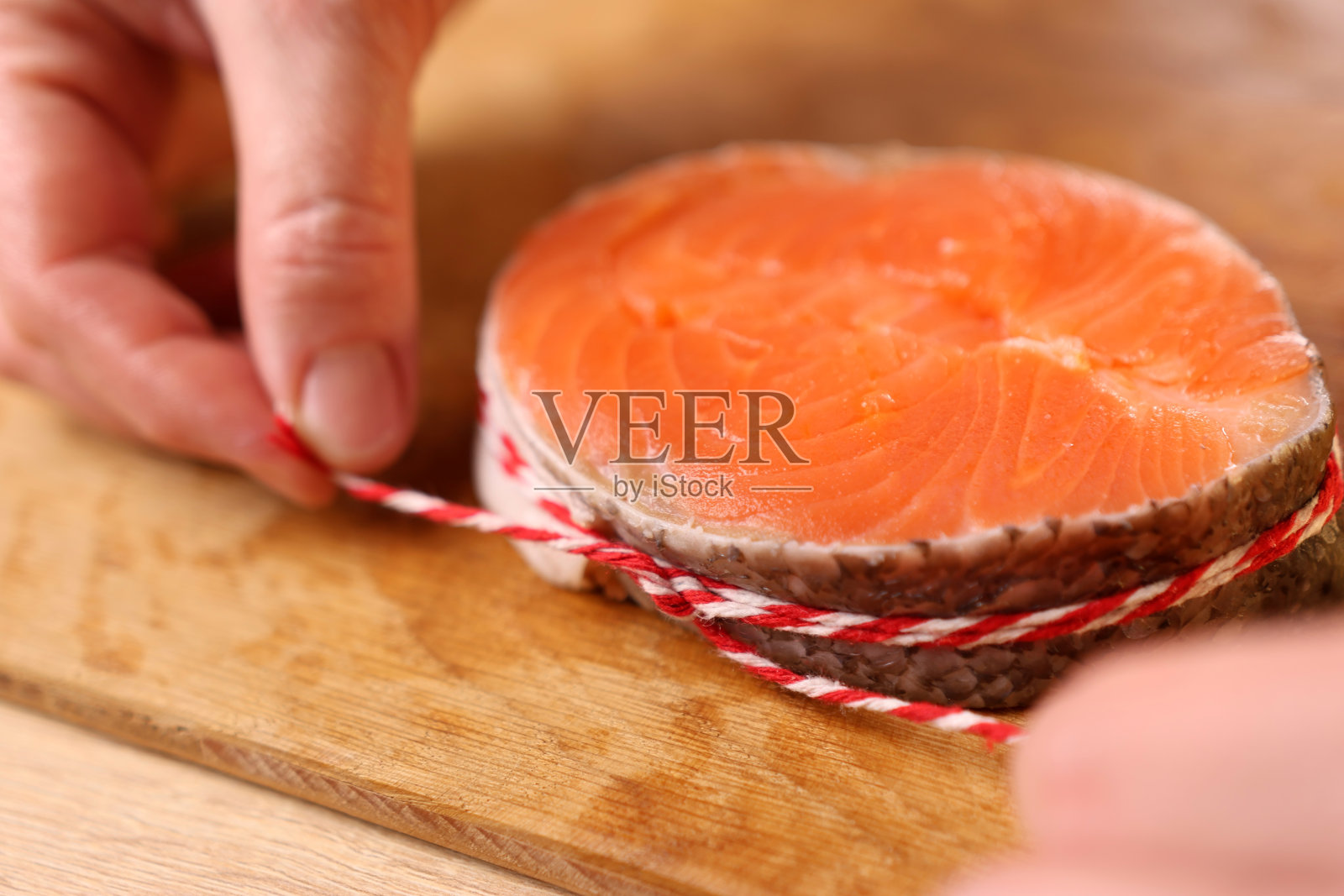 烤的时候,一块三文鱼被包成一个圈,然后用绳子绑起来照片摄影图片