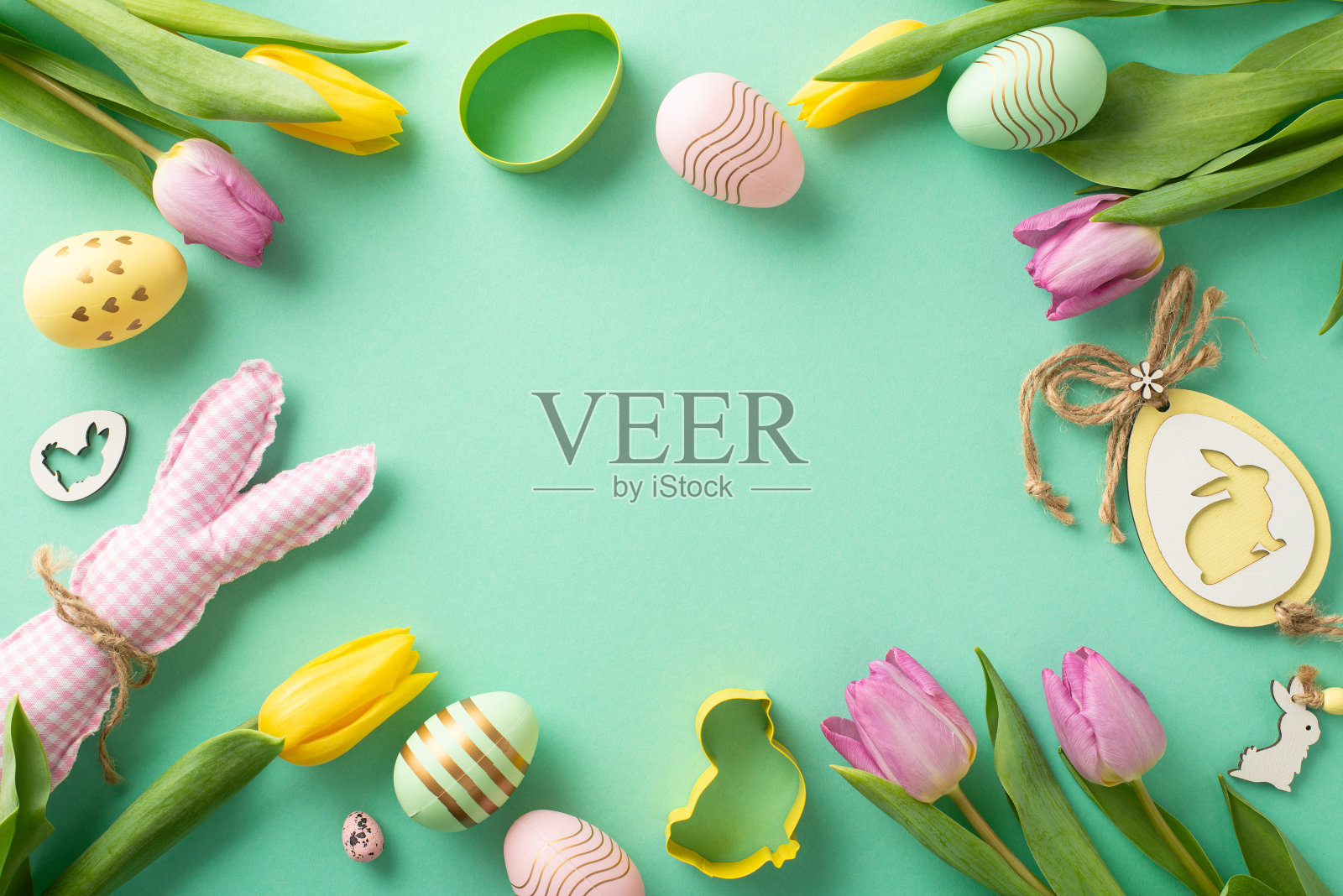 节日复活节欢乐场景:顶部视图充满活力的鸡蛋,兔子雕像,各种饼干切碎机,主题装饰和郁金香在蓝绿色的背景。为文字或促销留出足够的空间照片摄影图片