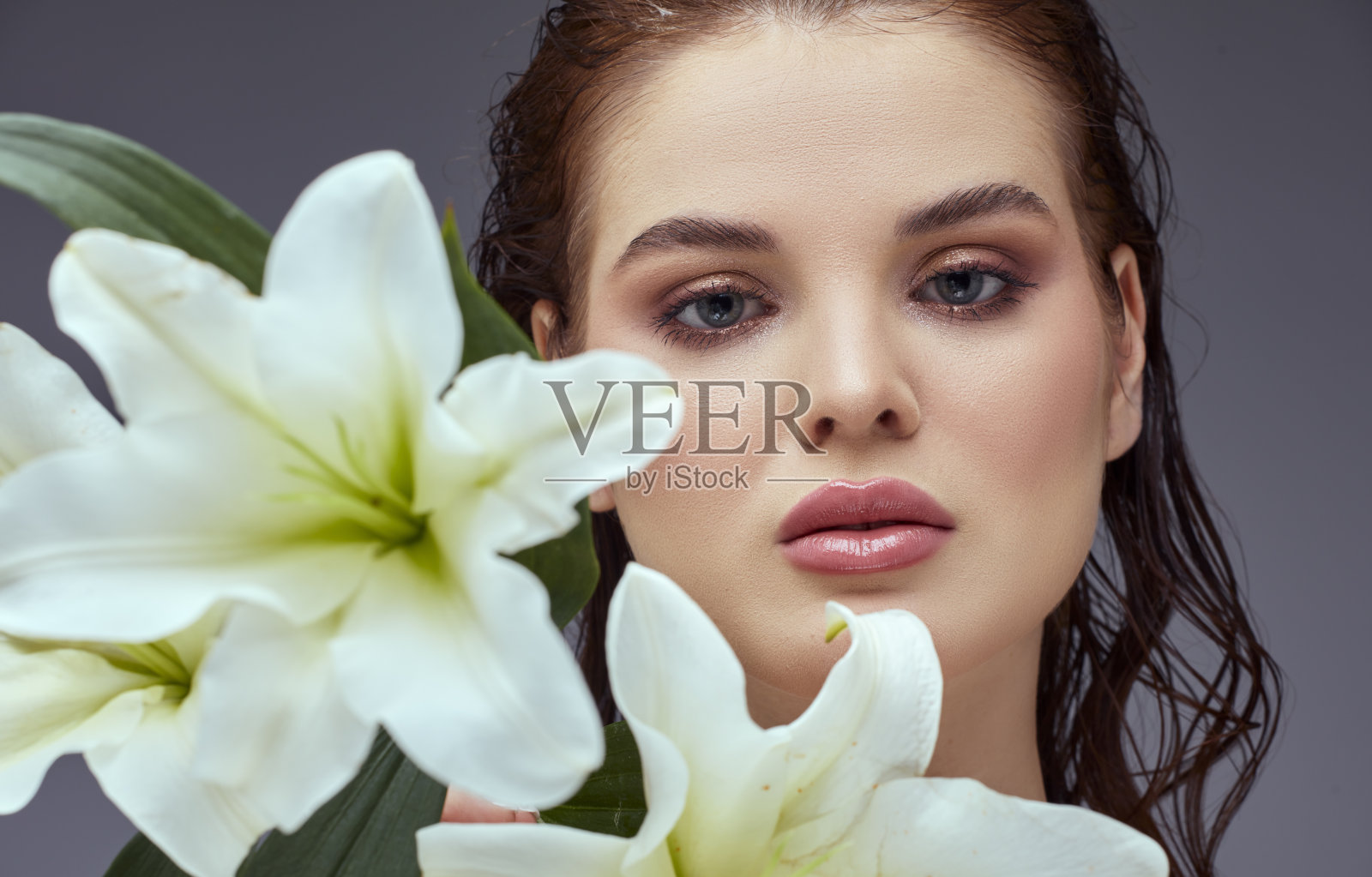 一个美丽的女人的画像,皮肤干净,脸上拿着一束花。照片摄影图片