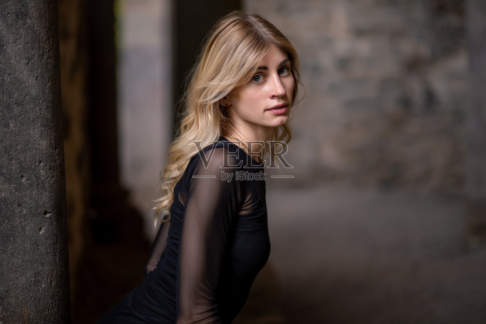 穿黑裙子的金发女孩回头看照片摄影图片