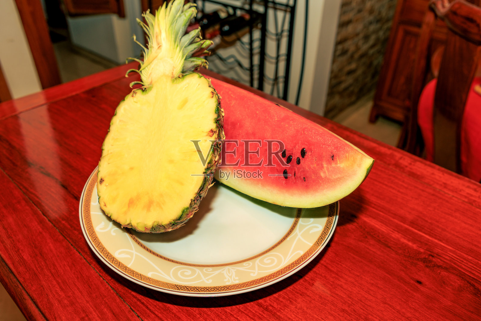 即食热带水果——一块西瓜和半个菠萝放在闪亮的红木桌上照片摄影图片