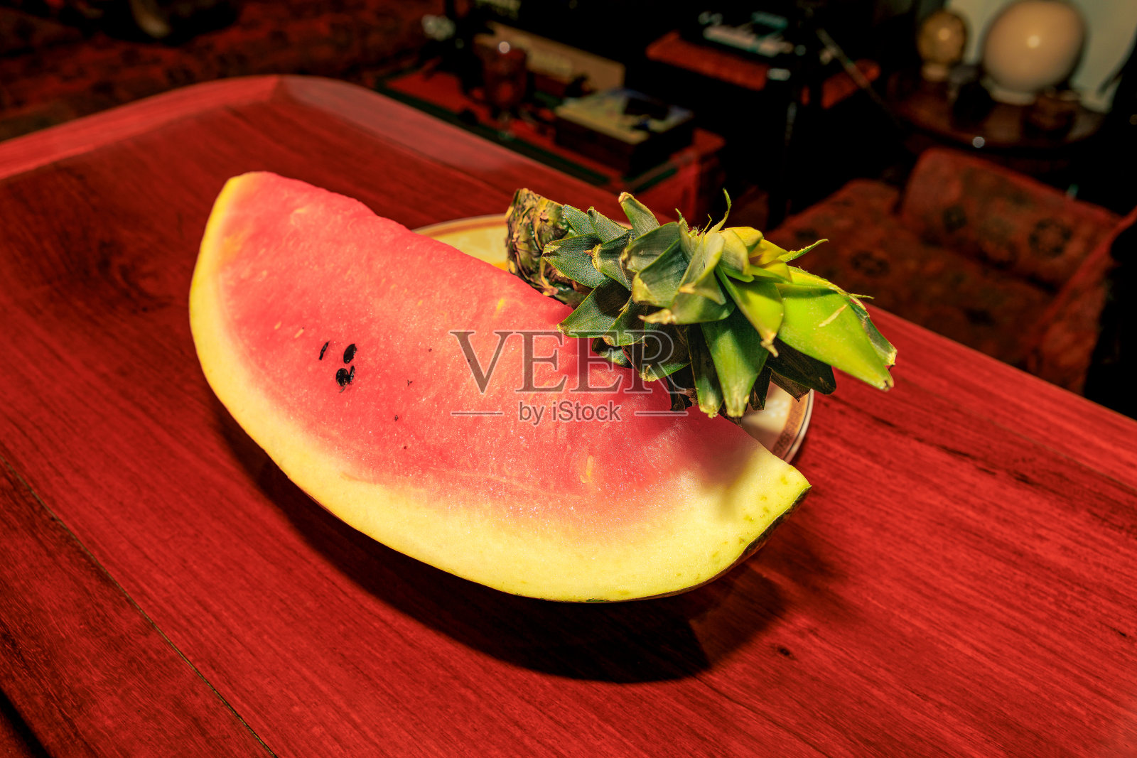 即食热带水果——一块西瓜和半个菠萝放在闪亮的红木桌上照片摄影图片
