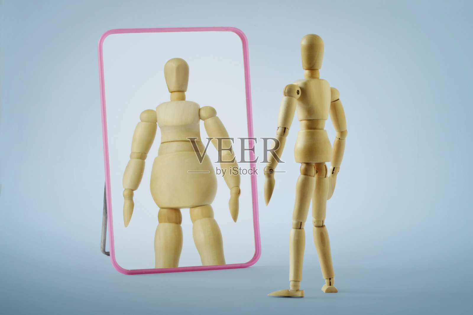 苗条的木制假人看着镜子,看到自己是肥胖的厌食症和饮食失调的概念照片摄影图片