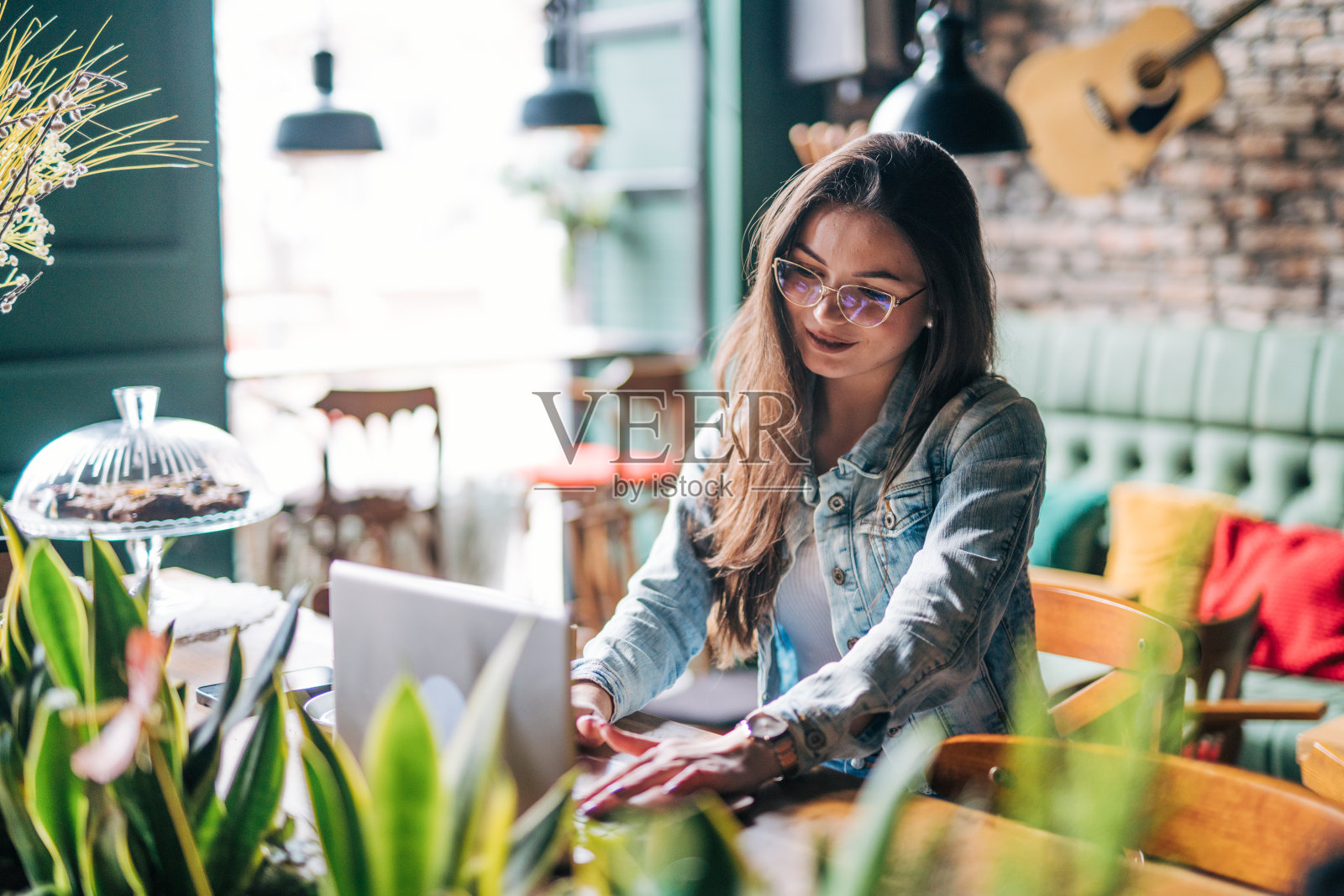一位年轻女子在咖啡馆里用笔记本电脑工作。照片摄影图片