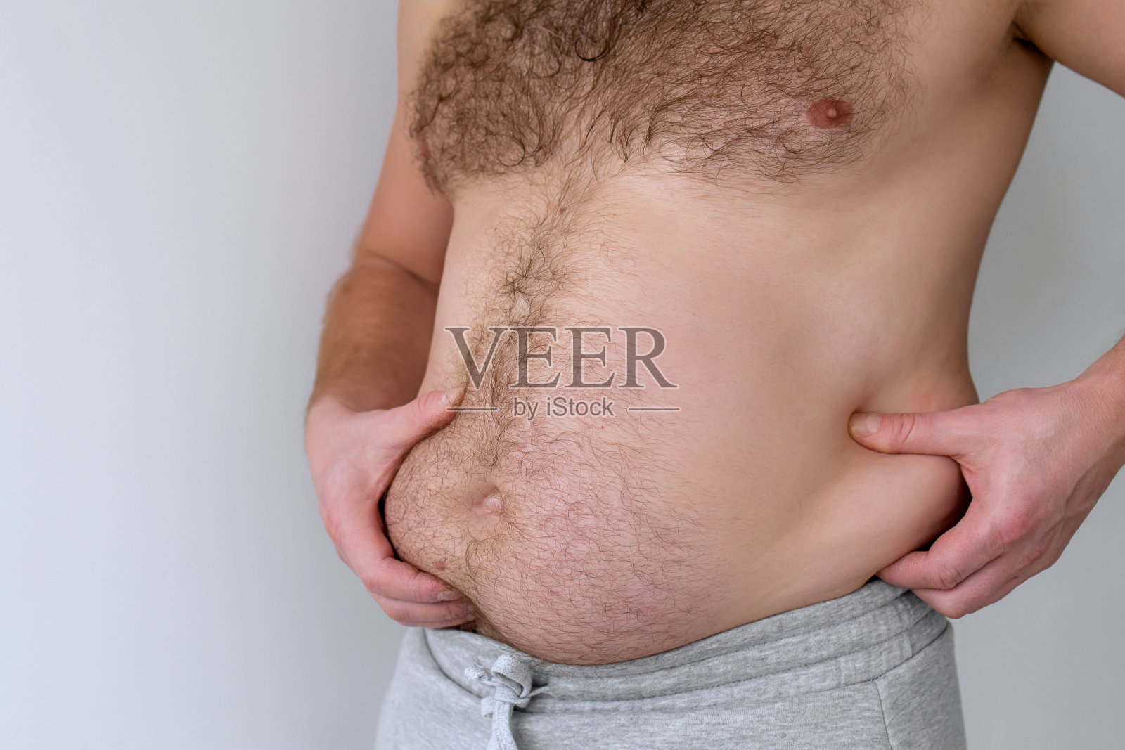 裸胖大肚子的男人摇着肚子上的脂肪褶皱,肥胖,健康,啤酒肚。身体的问题部位。荷尔蒙。超重。肥胖。本空间照片摄影图片