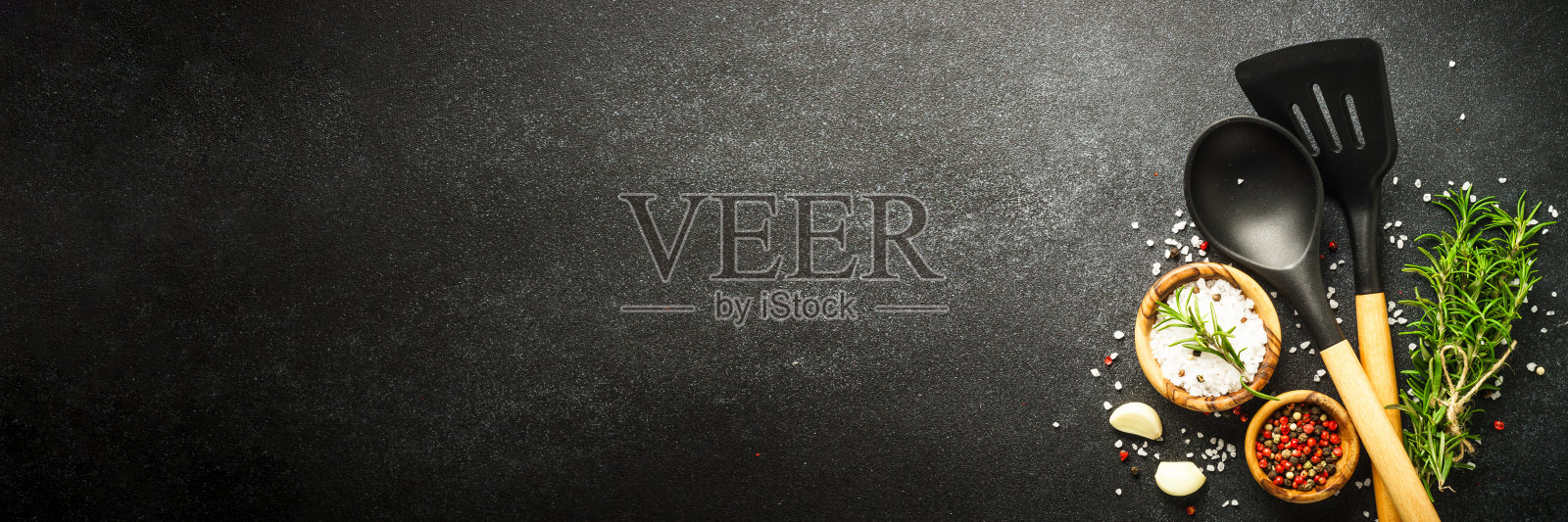 Food background with spices, herbs and utensil on black background.照片摄影图片