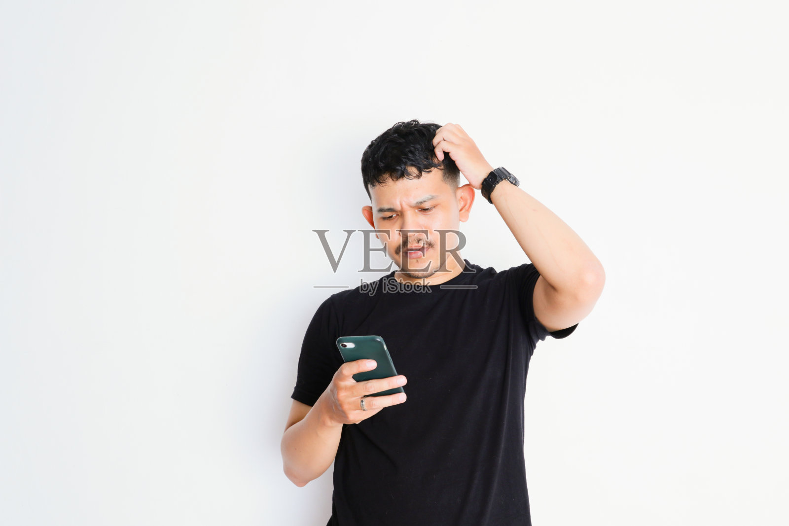 一个不开心的亚洲男人,穿着黑色衬衫,拿着手机,脸上带着悲伤的表情照片摄影图片