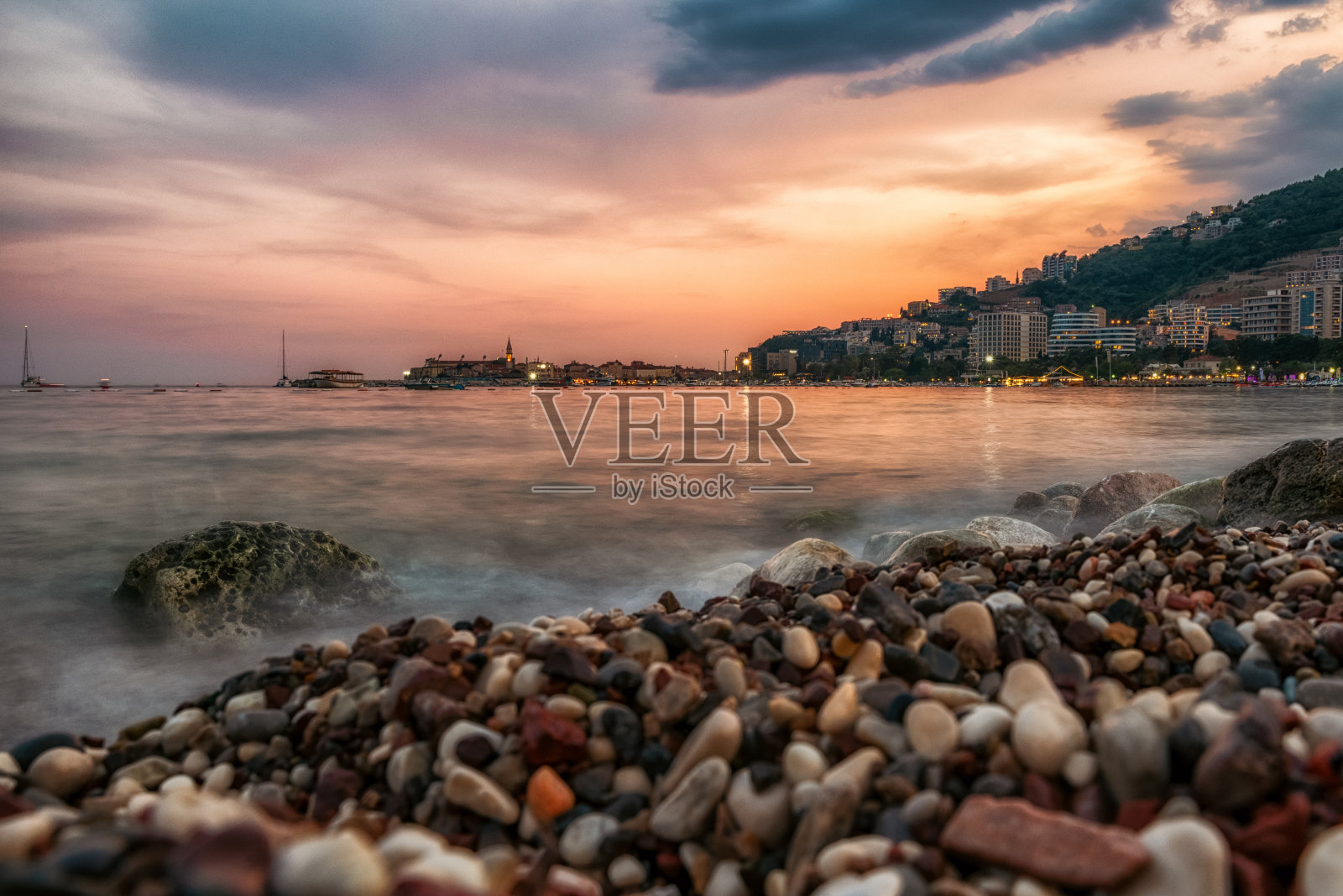 在黑山布德瓦度假胜地的卵石海滩上,五颜六色的日落照片摄影图片