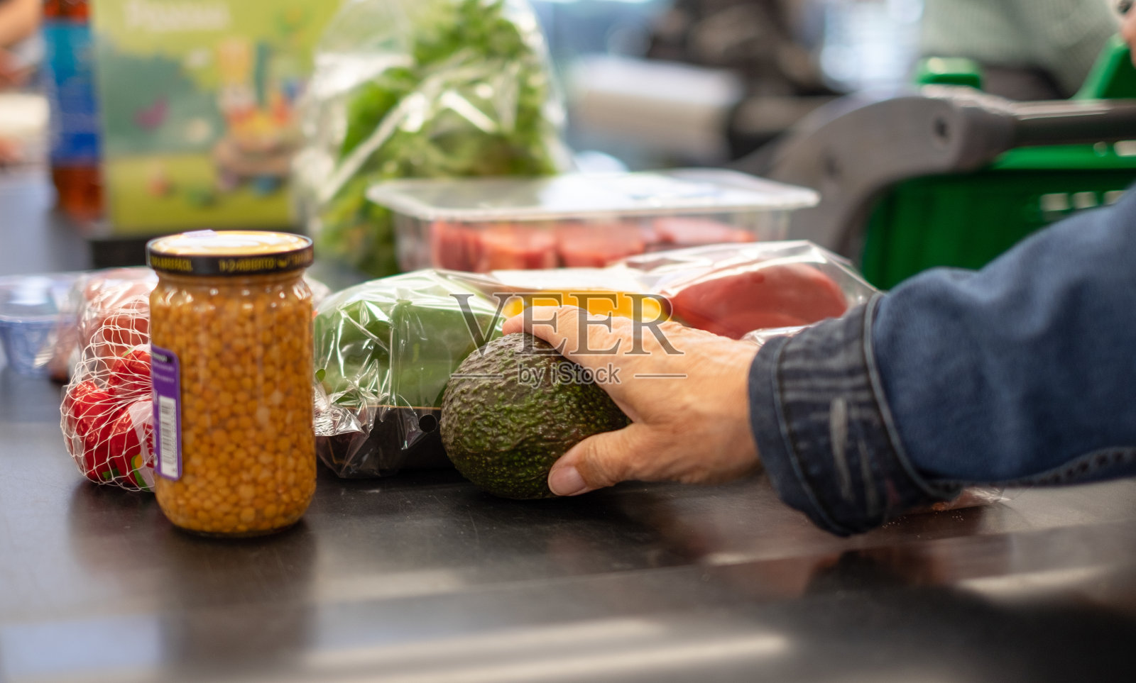 一位年长的白人妇女拿着一个成熟的鳄梨在超市柜台上摆放商品照片摄影图片