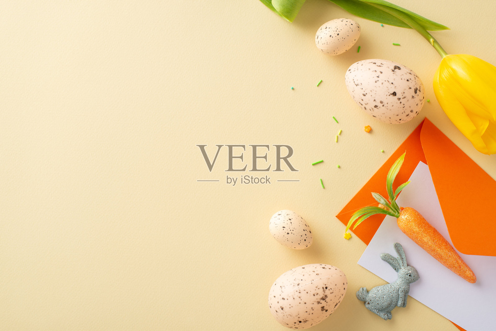 诱人的复活节设计。信封的俯视图,复活节兔子,彩蛋,用来装饰的胡萝卜,糖屑,柔软的米色表面上的郁金香,空白的地方是文字或广告照片摄影图片