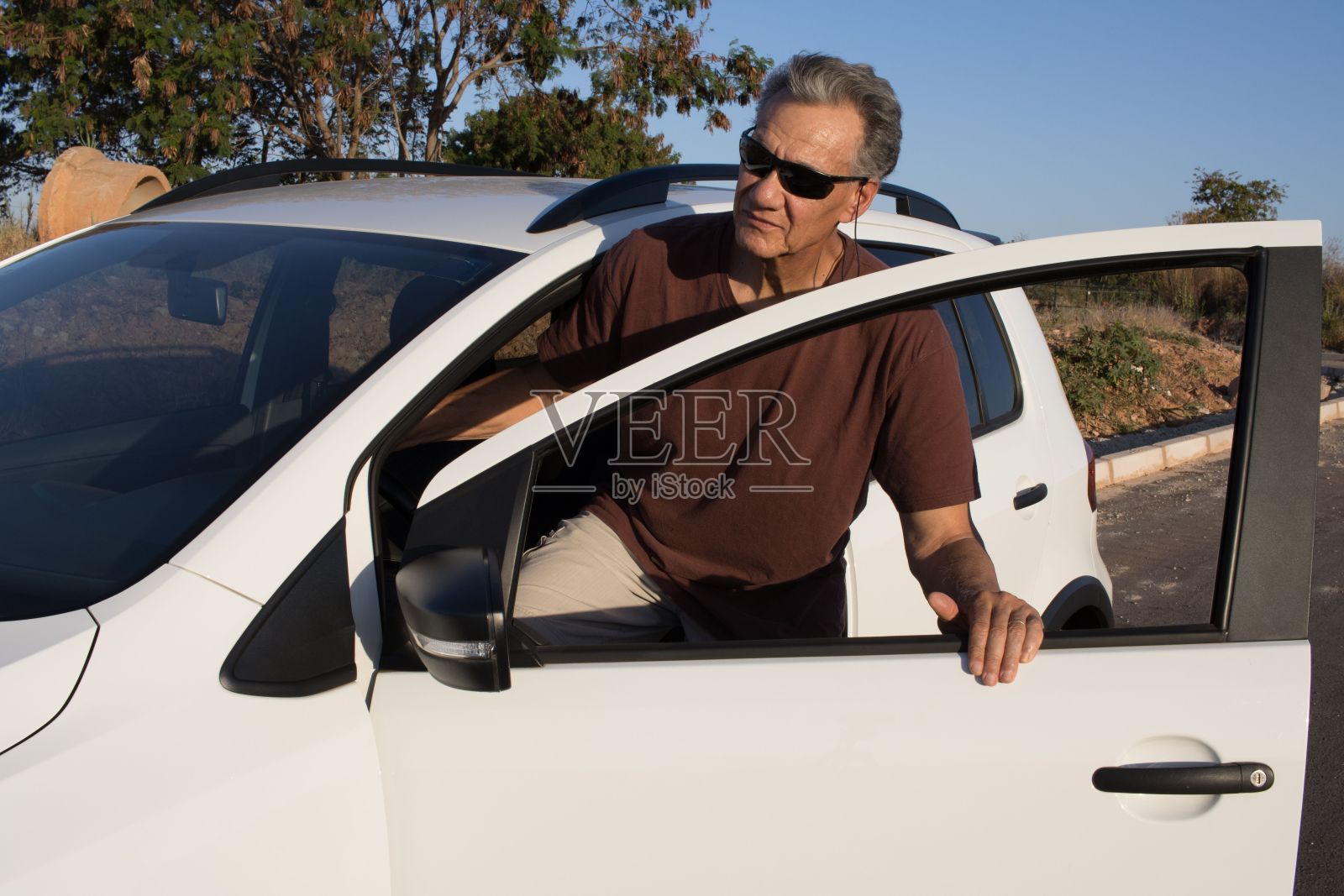 一个男人站在一辆白色轿车旁边,看着窗外照片摄影图片