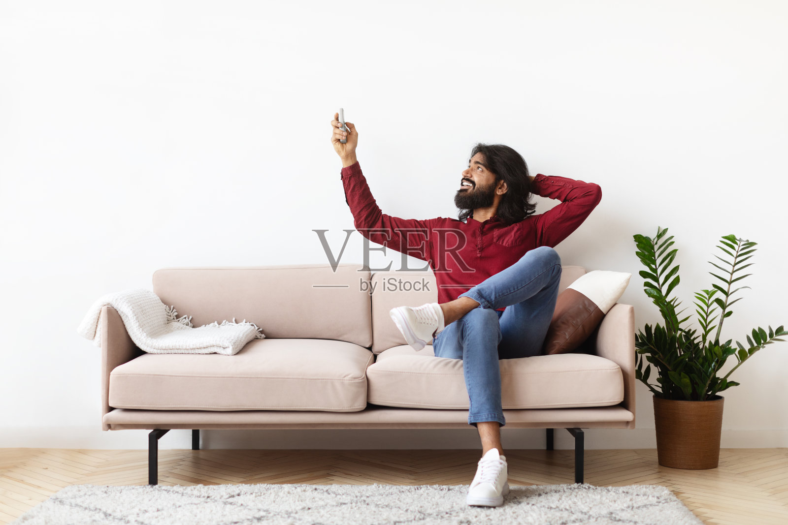 满意的印度人拿着遥控器在空调下放松照片摄影图片