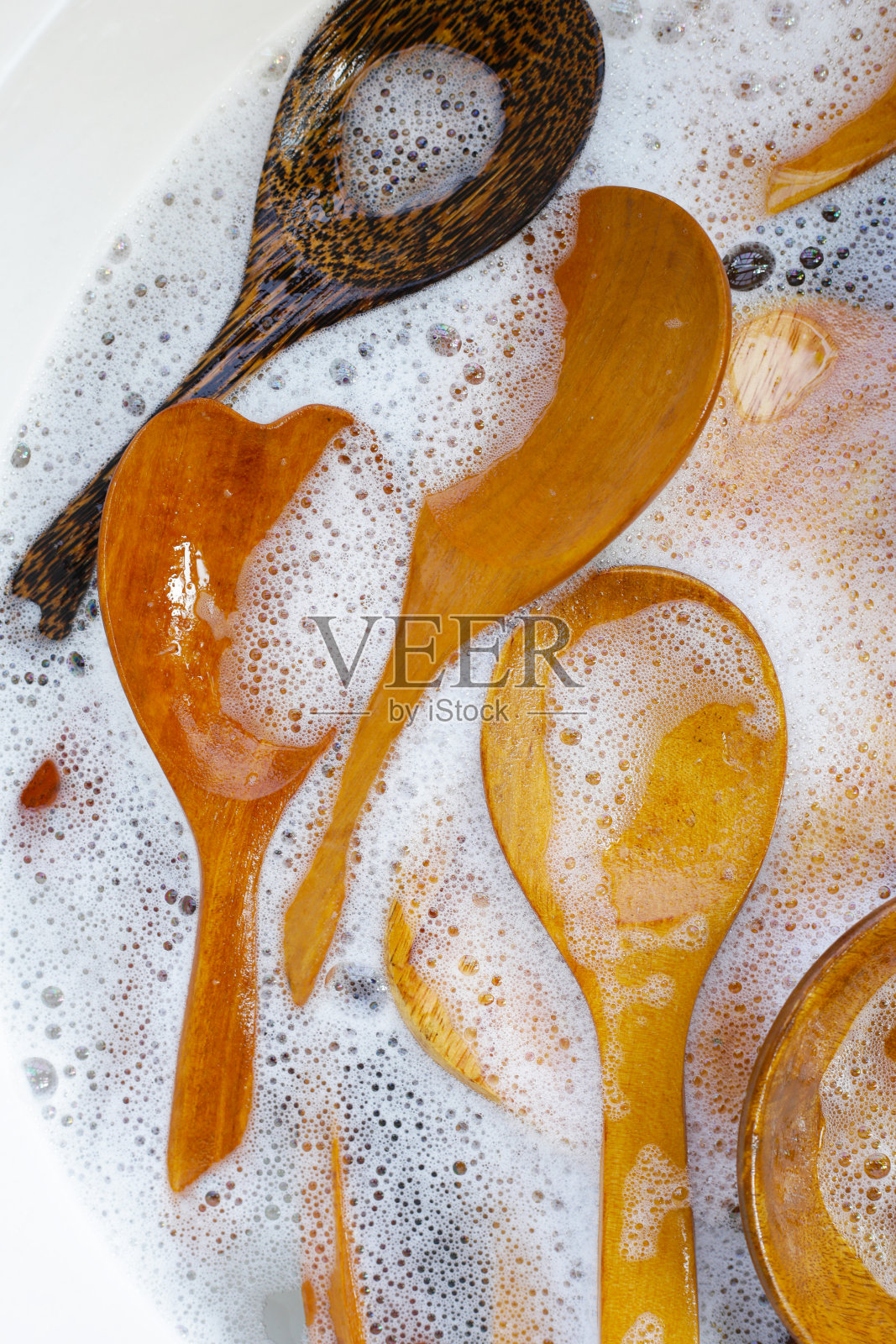 木制厨具浸在水中,还有洗碗液的气泡照片摄影图片