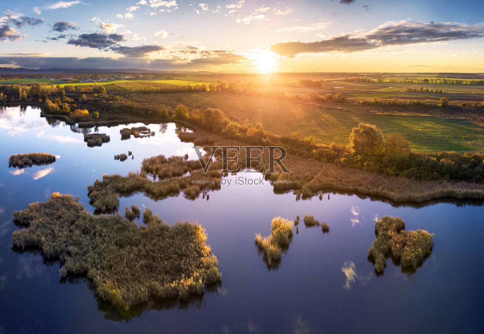 夕阳下的森林湖。沼泽中的野湖,无人机视野。有湖泊的乡村景观。森林在沼泽。照片摄影图片