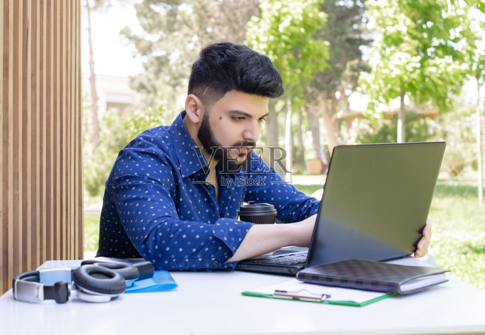 留着胡子的黑发男性坐在电脑前,打字。照片摄影图片