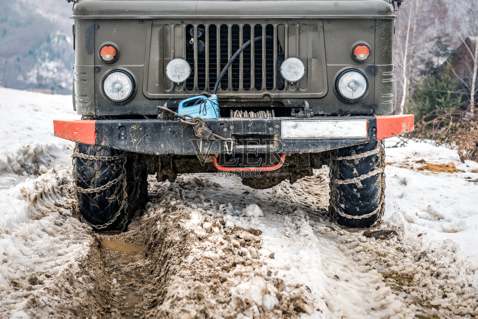 复古军用卡车与雪和泥链车轮在冬季山区照片摄影图片