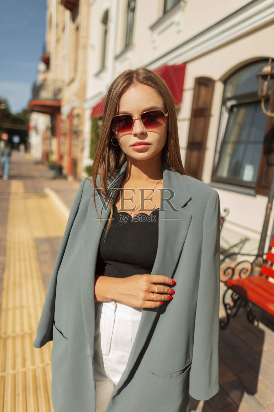 成功的都市美女商务女孩,戴着复古太阳镜,穿着时尚的衣服,在一个阳光明媚的春日走在城市里照片摄影图片