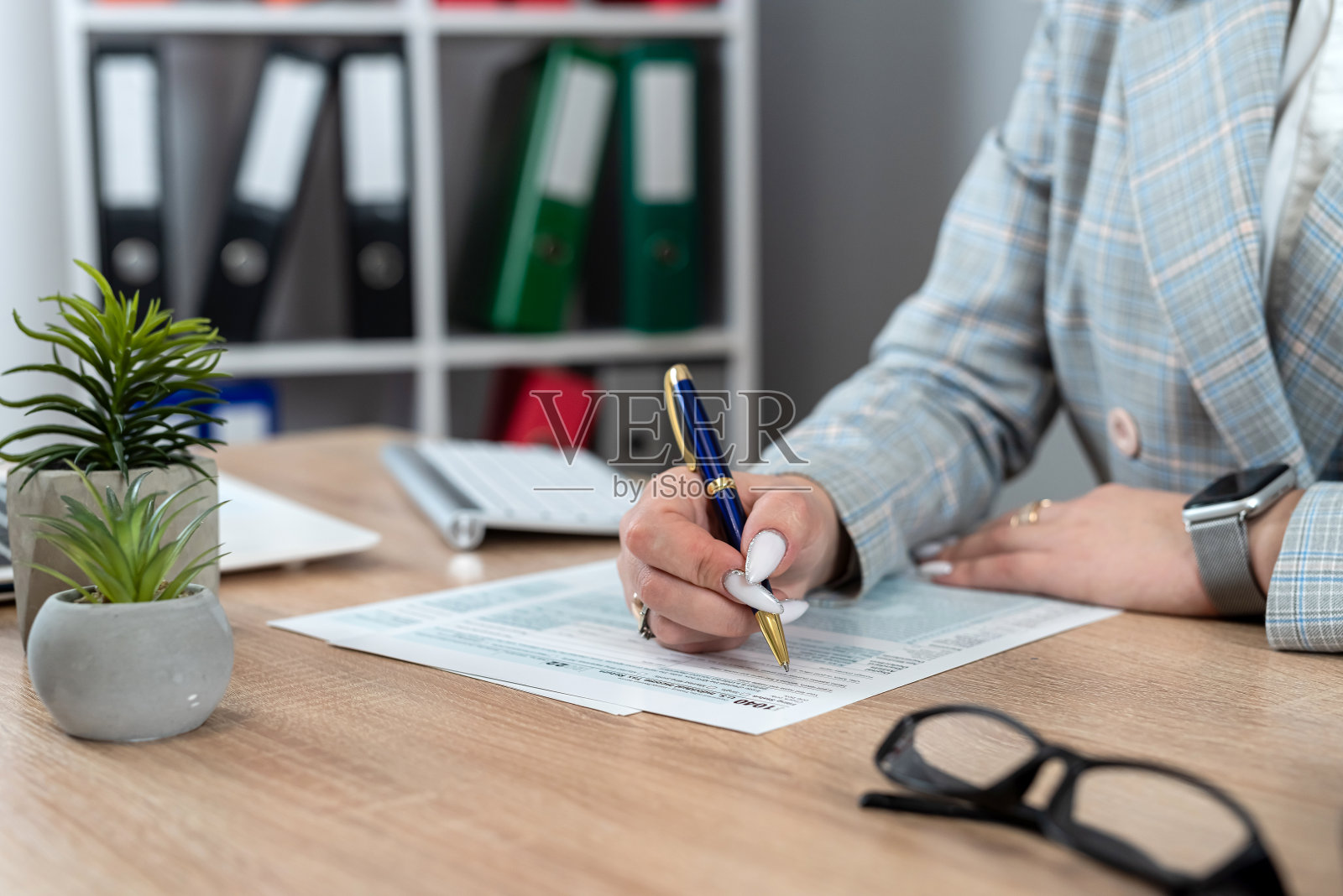 女手在办公室用计算器填写1040个税表照片摄影图片