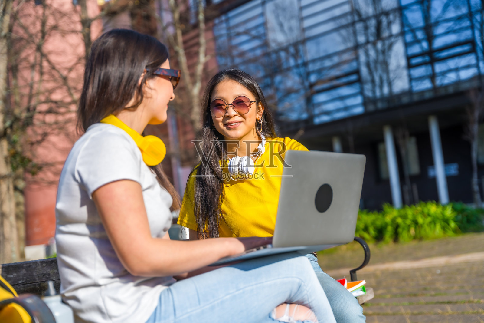 坐在学校外面用笔记本电脑的朋友照片摄影图片