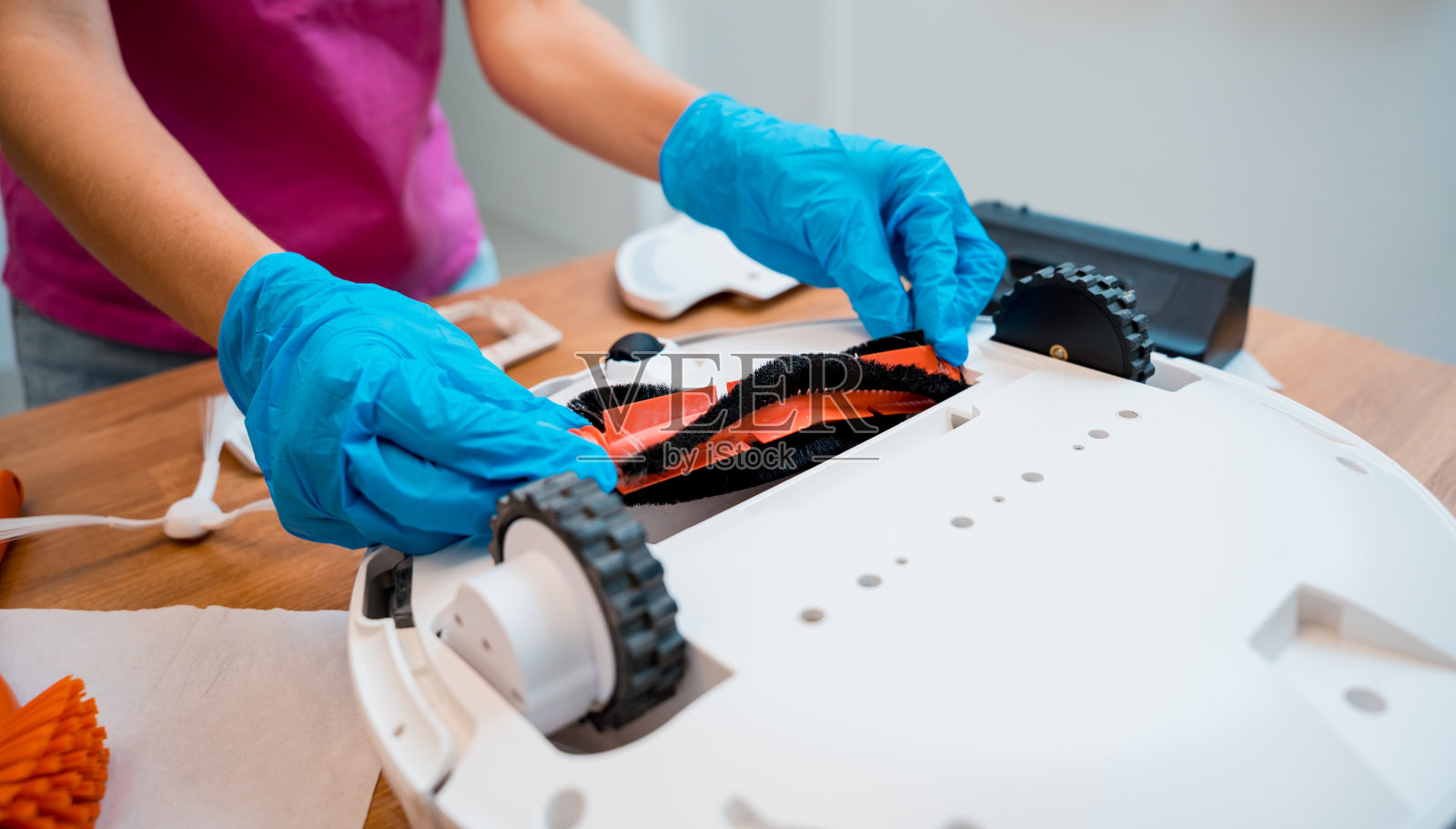 一名年轻女子清洁机器人吸尘器后的污垢。照片摄影图片
